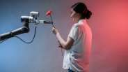 Woman interacts with a robotic arm holding flower