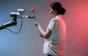 Woman interacts with a robotic arm holding flower