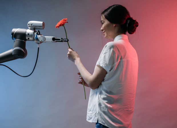 Woman interacts with a robotic arm holding flower